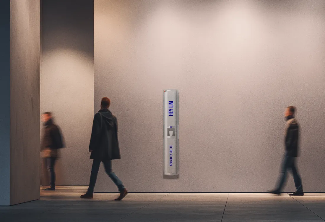 HEYLIM specialty coffee pillar in a minimalist museum corridor with visitors walking past in warm light