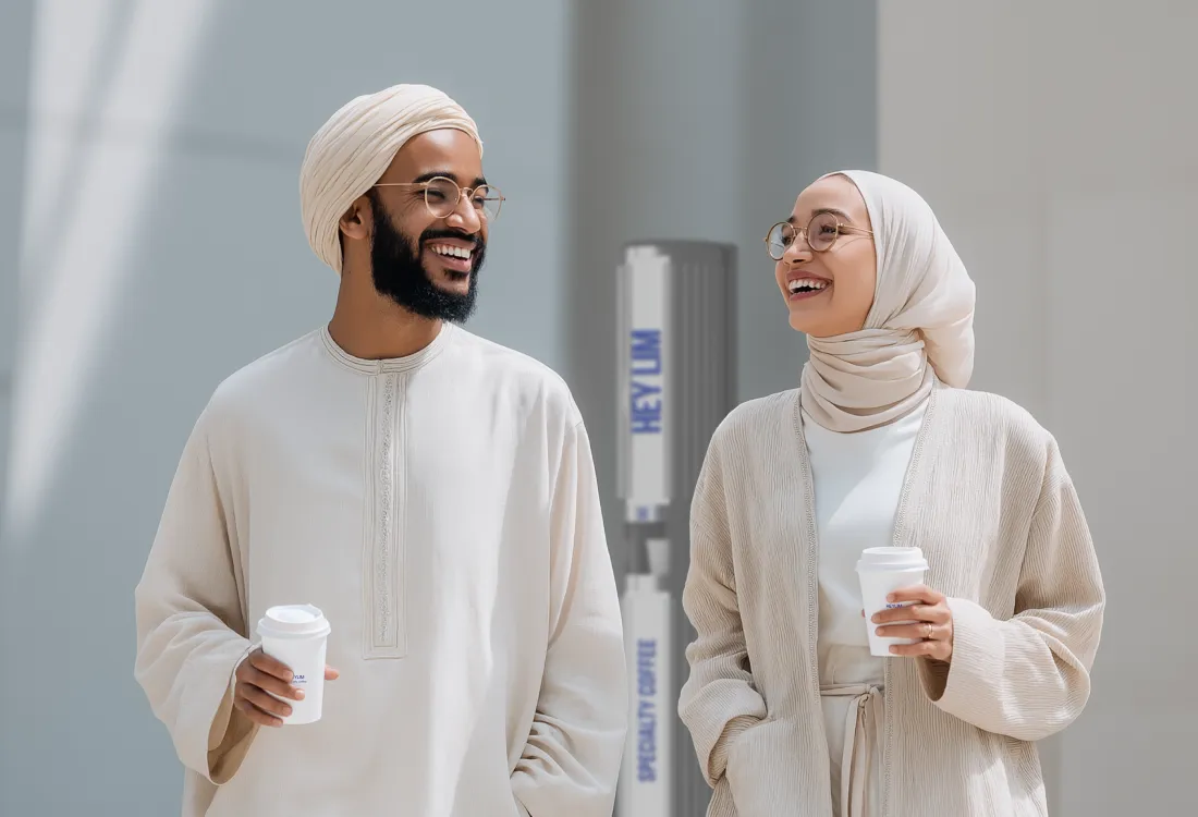 Emirati couple holding coffee cups from a HEYLIM autonomous café — traditional dress meets modern coffee culture